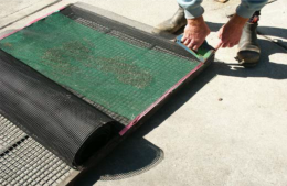 Oyster mesh cover being stapled into place to protect oyster spat mesh bags secured in place in tray